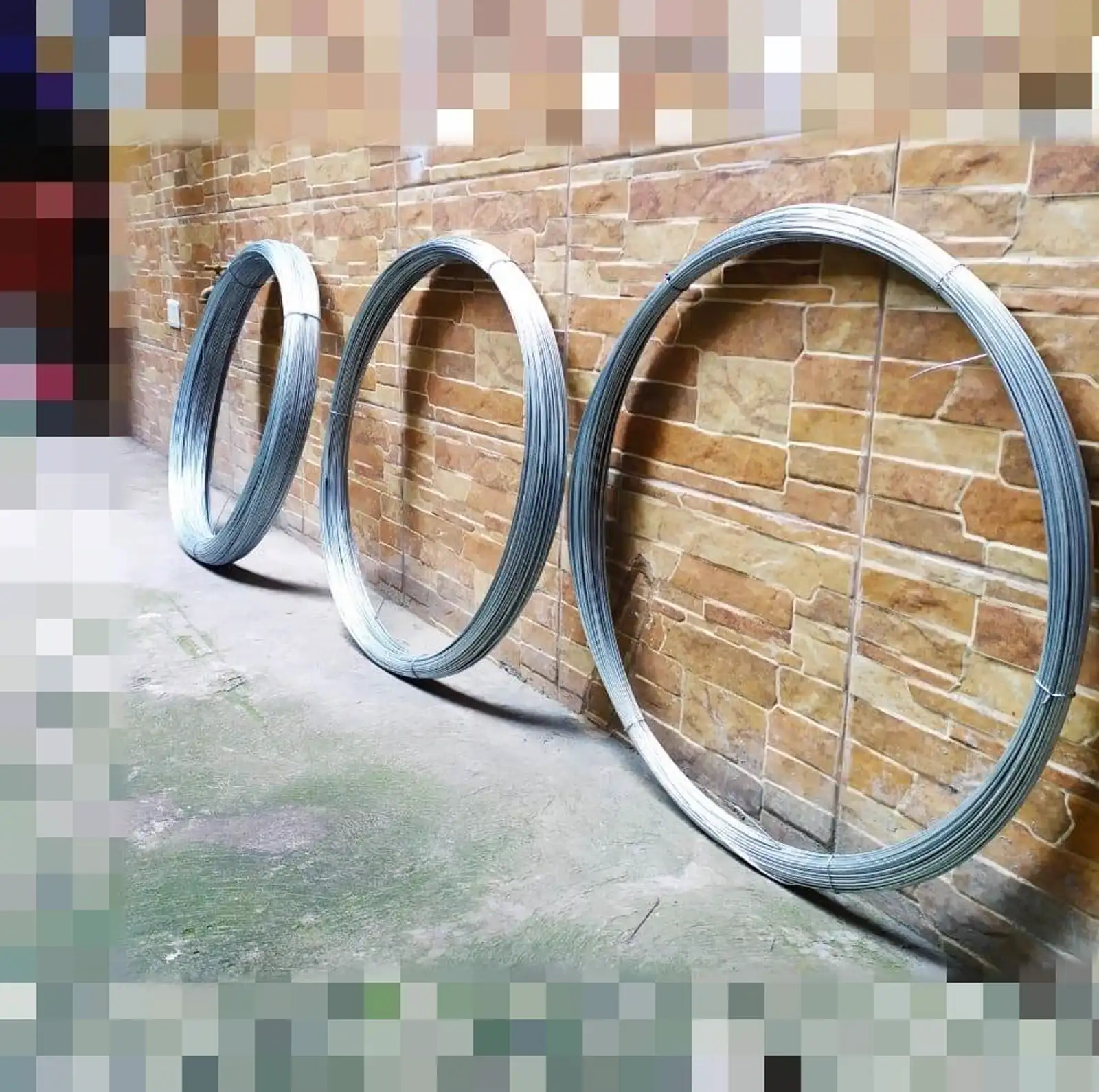 Tres rollos de alambre de distintos diámetros apoyados en una pared
